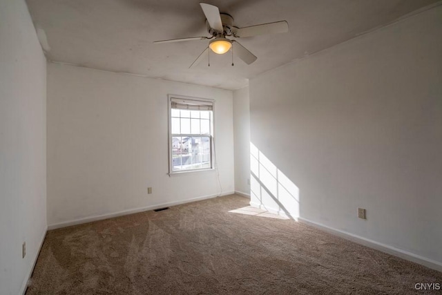 empty room with carpet flooring, visible vents, baseboards, and ceiling fan