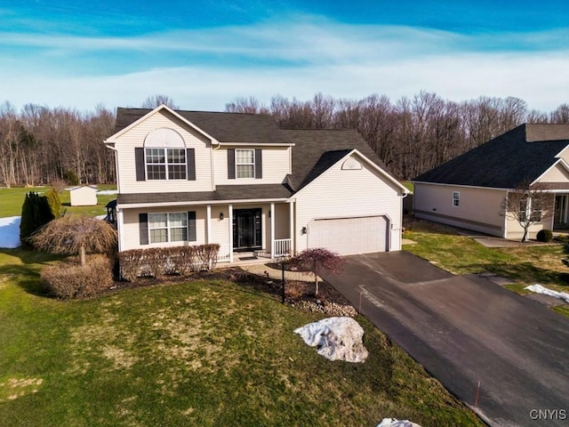 traditional home featuring aphalt driveway, a porch, and a front yard