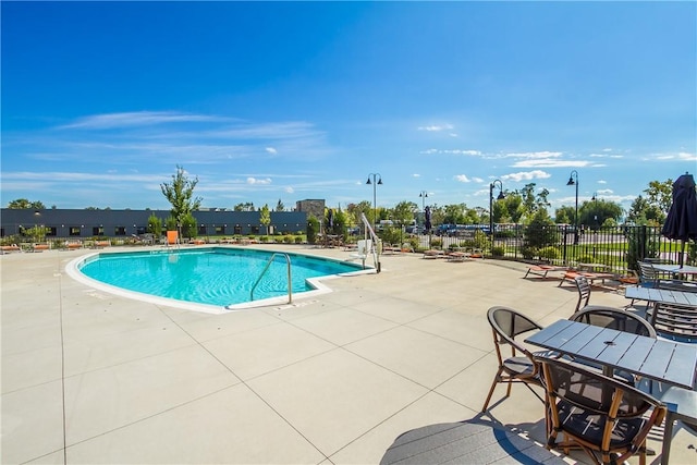 community pool with a patio area and fence