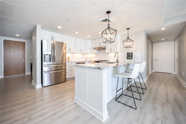 kitchen featuring visible vents, light wood-type flooring, under cabinet range hood, white cabinetry, and stainless steel fridge with ice dispenser