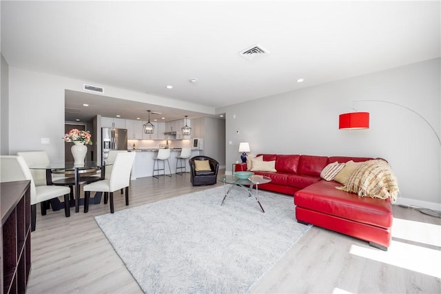 living room with recessed lighting, visible vents, and light wood-style flooring