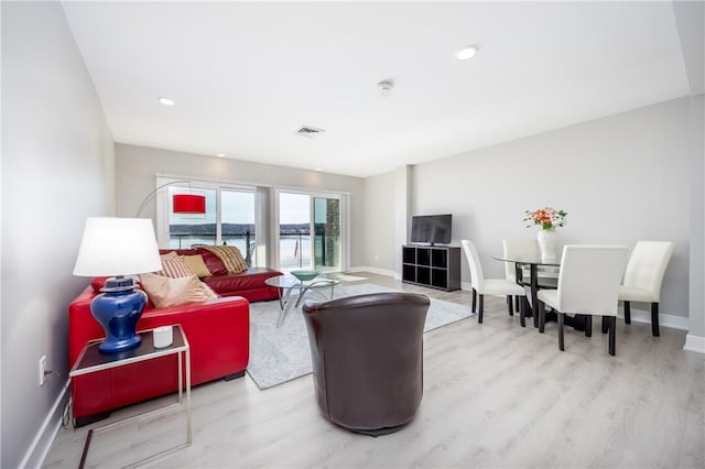 living area featuring wood finished floors, visible vents, and baseboards