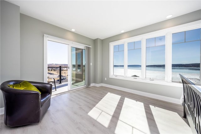 sitting room featuring recessed lighting, wood finished floors, baseboards, and a water view