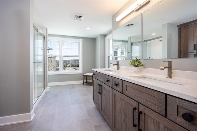 bathroom with a shower stall, baseboards, visible vents, and a sink