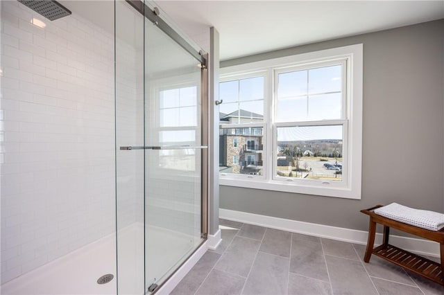 full bath featuring a shower stall, tile patterned floors, baseboards, and a wealth of natural light