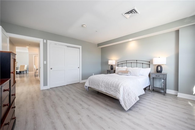 bedroom featuring visible vents, baseboards, light wood-style floors, and a closet