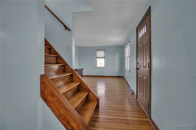 foyer entrance with stairway, wood finished floors, and baseboards