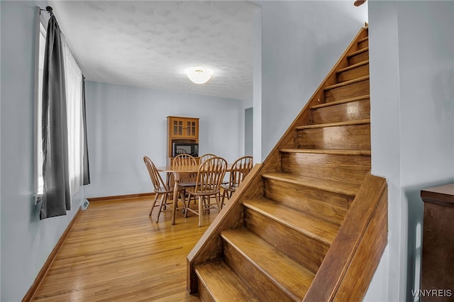 stairway with wood finished floors, baseboards, and a textured ceiling