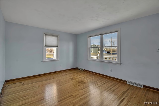 empty room with visible vents, baseboards, and wood finished floors