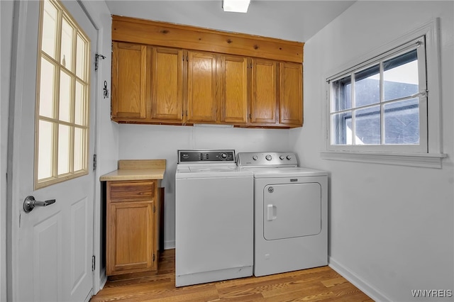 washroom with washer and clothes dryer, cabinet space, and light wood-style flooring