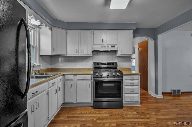 kitchen featuring visible vents, stainless steel range with gas cooktop, freestanding refrigerator, a sink, and under cabinet range hood