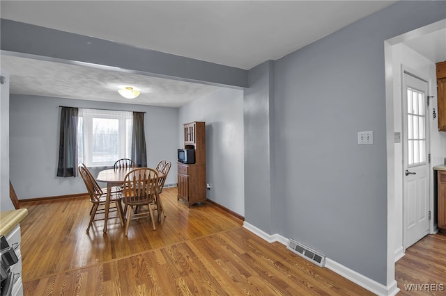 dining area with visible vents, baseboards, and light wood finished floors