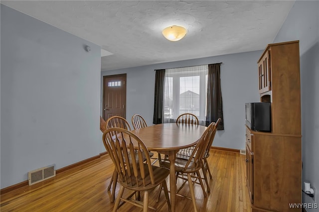 dining area with visible vents, a textured ceiling, baseboards, and light wood-style floors