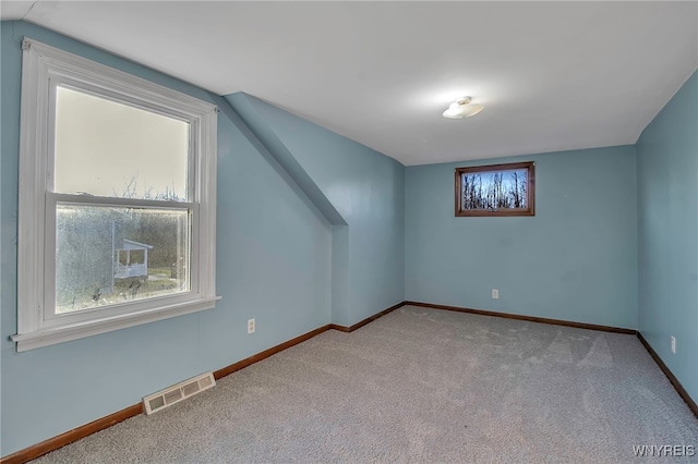 additional living space with visible vents, baseboards, lofted ceiling, and carpet flooring