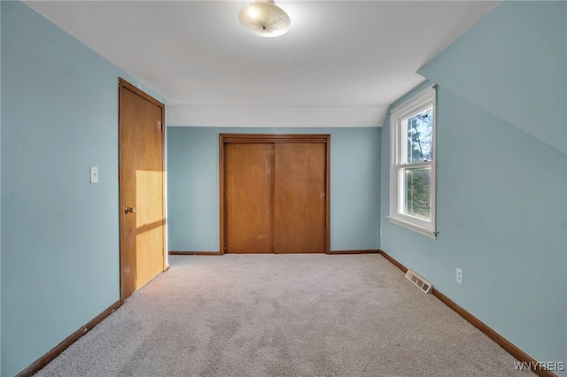 unfurnished bedroom featuring visible vents, baseboards, vaulted ceiling, carpet floors, and a closet