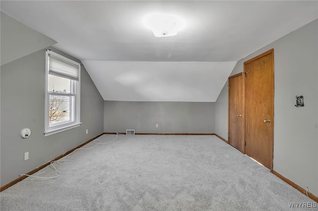 additional living space featuring visible vents, carpet flooring, lofted ceiling, and baseboards