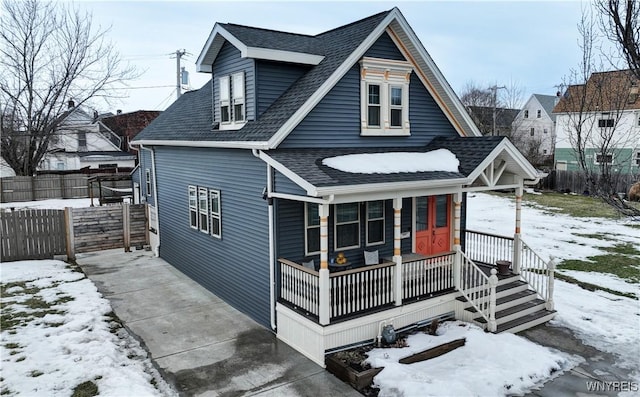 bungalow-style home with a porch, fence, and a shingled roof