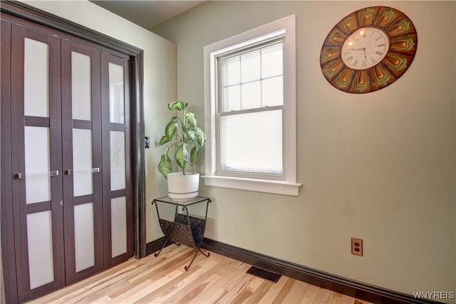 foyer entrance featuring visible vents, light wood-type flooring, and baseboards