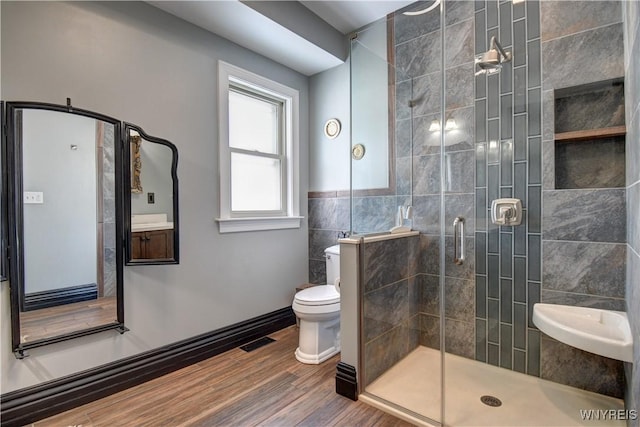 bathroom featuring wood finished floors, visible vents, a stall shower, tile walls, and toilet