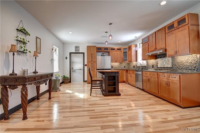 kitchen with brown cabinetry, a kitchen bar, appliances with stainless steel finishes, and decorative backsplash