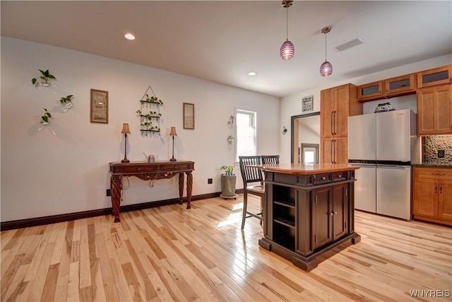 kitchen featuring tasteful backsplash, light wood-style flooring, and freestanding refrigerator