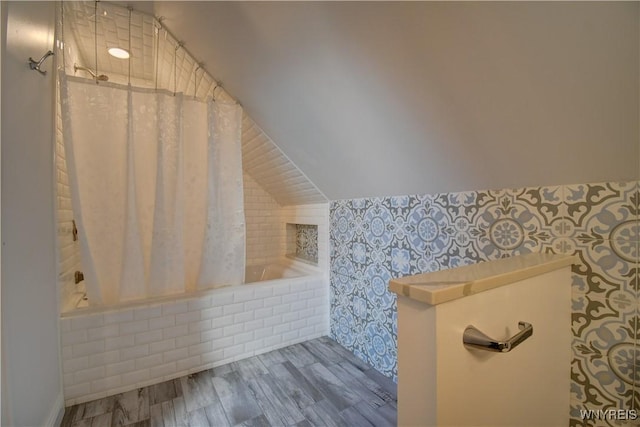 full bathroom with lofted ceiling, tiled shower / bath combo, and wood finished floors