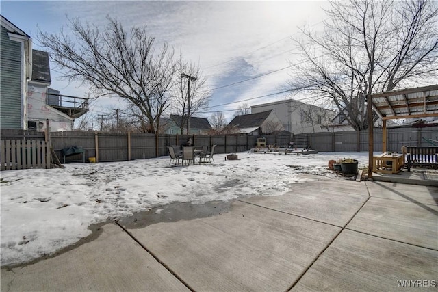 snowy yard with a patio, a fenced backyard, and outdoor dining space