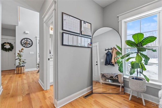 hallway with visible vents, light wood-type flooring, and baseboards