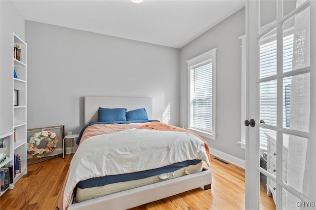 bedroom featuring visible vents, baseboards, and wood finished floors