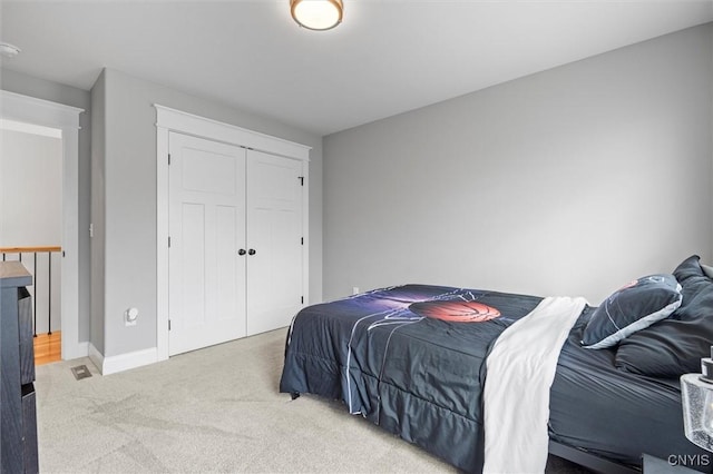 carpeted bedroom with a closet and baseboards