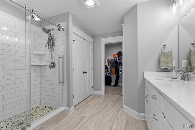 full bathroom with vanity, visible vents, baseboards, a stall shower, and a spacious closet