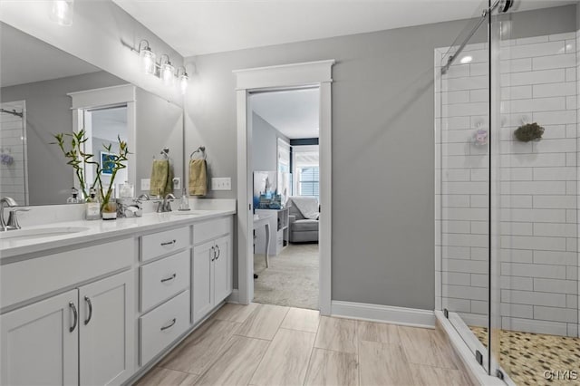 ensuite bathroom with a sink, baseboards, double vanity, and a shower stall