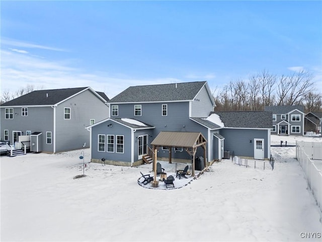 snow covered rear of property featuring a residential view, fence, and an outdoor fire pit