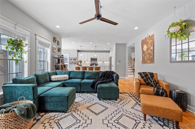 living area with light wood-type flooring, plenty of natural light, and stairs