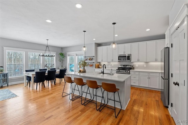 kitchen featuring a sink, decorative backsplash, light wood-style flooring, and stainless steel appliances