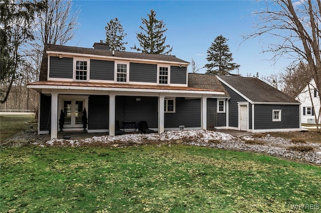 back of house with french doors, a chimney, and a yard