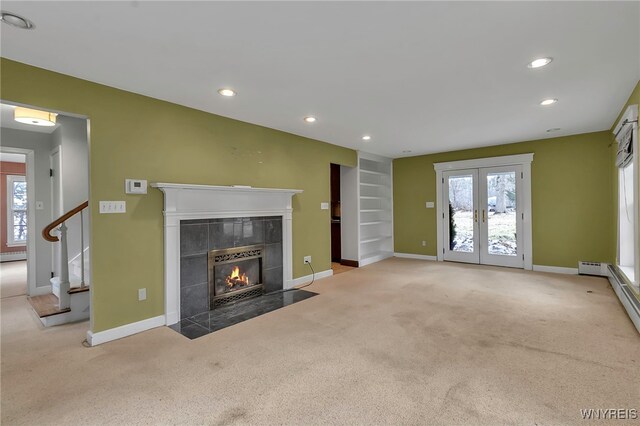 unfurnished living room featuring a tiled fireplace, a wealth of natural light, and carpet