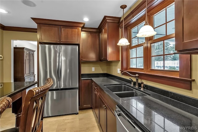 kitchen with dark stone counters, crown molding, appliances with stainless steel finishes, and a sink