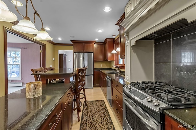 kitchen with decorative light fixtures, dark stone countertops, recessed lighting, appliances with stainless steel finishes, and a sink