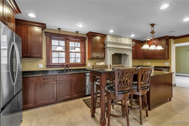 kitchen with dark countertops, light wood finished floors, baseboard heating, stainless steel appliances, and a sink