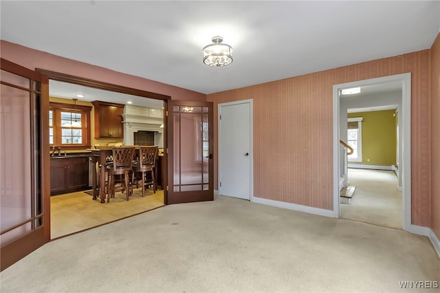 interior space with a sink, baseboards, baseboard heating, and light carpet