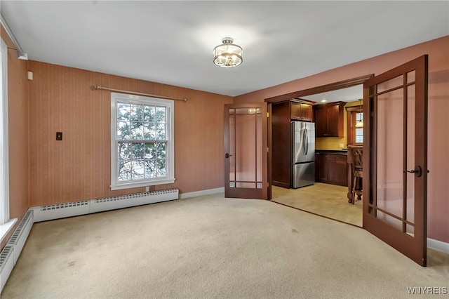 interior space featuring a baseboard heating unit, light carpet, french doors, freestanding refrigerator, and a baseboard radiator