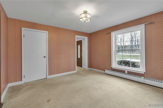 carpeted spare room with a baseboard heating unit and baseboards