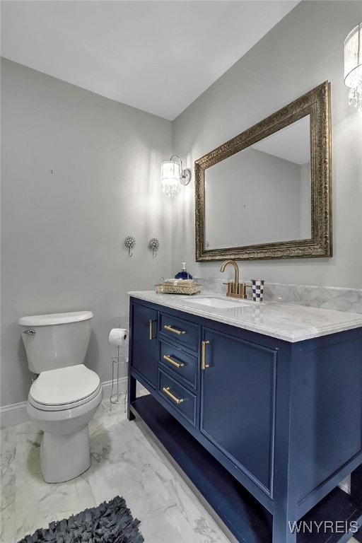 bathroom with vanity, toilet, baseboards, and marble finish floor