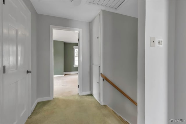 hall with a baseboard heating unit, baseboards, and light colored carpet