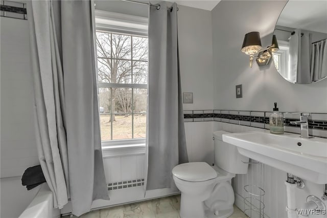 full bath featuring a wainscoted wall, marble finish floor, toilet, and shower / tub combo