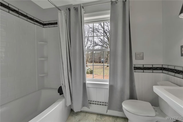 full bath with shower / bathtub combination with curtain, toilet, marble finish floor, and wainscoting