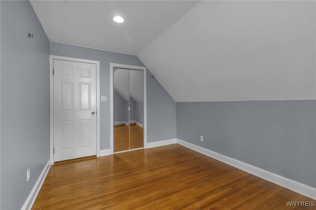 additional living space with baseboards, lofted ceiling, wood finished floors, and a baseboard radiator