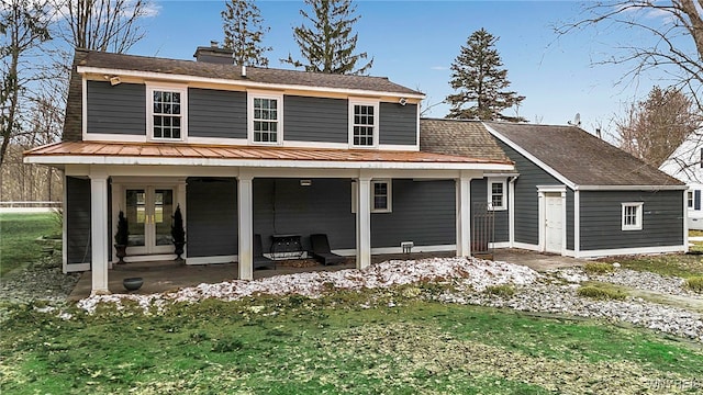 back of house with a standing seam roof, french doors, metal roof, a chimney, and a patio area