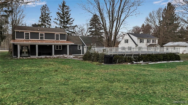 back of house with metal roof, a lawn, a chimney, and a standing seam roof